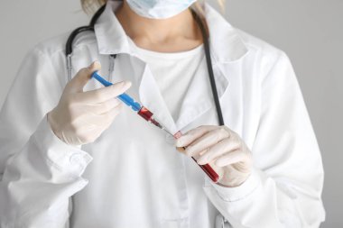 Klinikte şırınga ve test tüpü tutan laboratuvar asistanı, yakın plan.