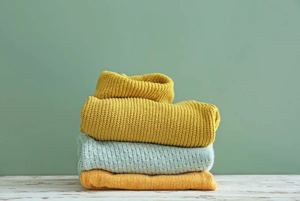 Set of warm winter clothes on table against color background — Stock Photo, Image