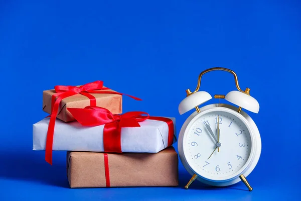 Alarm clock with Christmas gifts on color background Stock Photo
