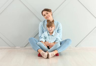 Mutlu anne ve kızın portresi duvarın yanında oturuyor.