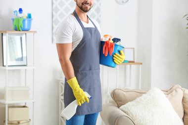Odasında temizlik malzemesi olan erkek hademe.