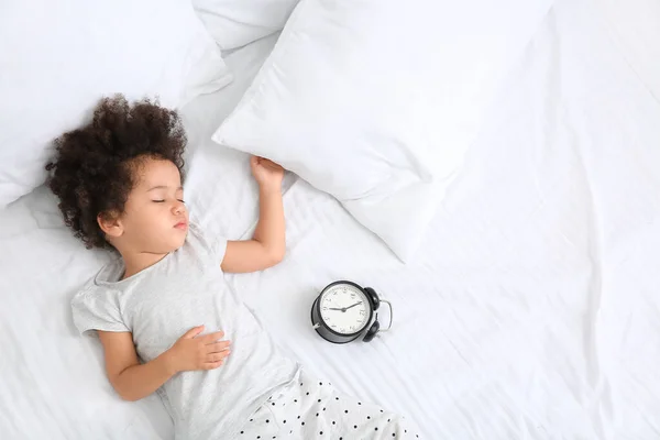 ベッドで眠っている目覚まし時計を持つ小さなアフリカ系アメリカ人の女の子 — ストック写真