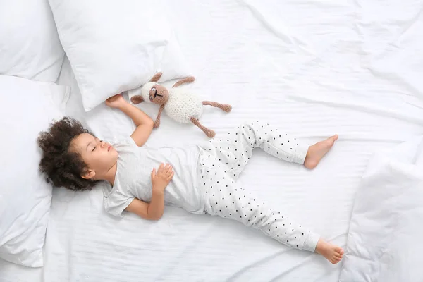 Μικρό Αφροαμερικανό κορίτσι με παιχνίδι που κοιμάται στο κρεβάτι — Φωτογραφία Αρχείου