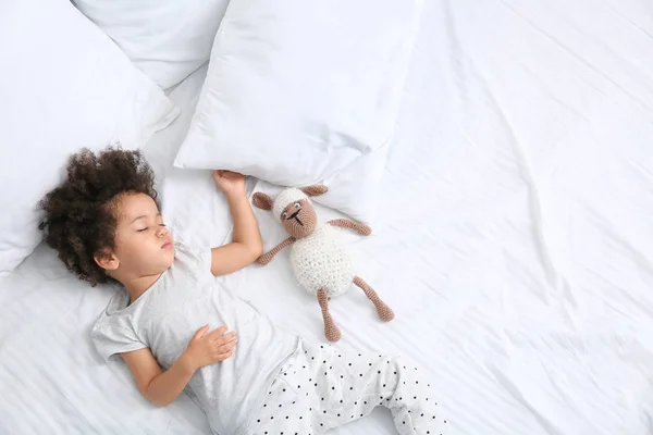 Petite fille afro-américaine avec jouet dormant au lit — Photo