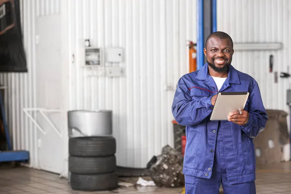 African-American mechanic with tablet computer in car service center — Stock Photo, Image