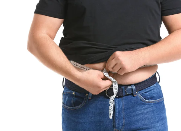 Uomo sovrappeso che misura la sua vita su sfondo bianco. Perdita di peso concetto — Foto Stock