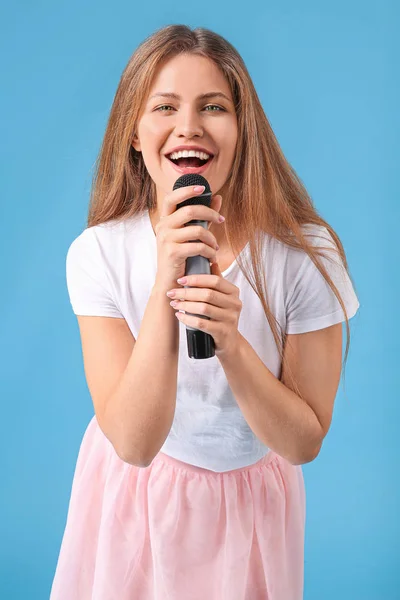 Gyönyörű fiatal női énekes mikrofonnal színes háttér — Stock Fotó