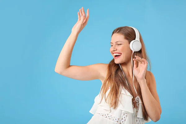 Mooie jonge vrouw luisteren naar muziek op kleur achtergrond — Stockfoto