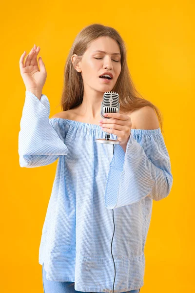 Linda jovem cantora com microfone no fundo de cor — Fotografia de Stock