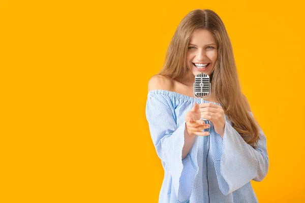 Hermosa joven cantante femenina con micrófono sobre fondo de color —  Fotos de Stock