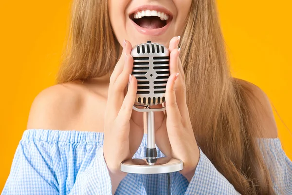 Hermosa joven cantante femenina con micrófono sobre fondo de color, primer plano —  Fotos de Stock