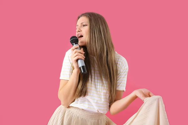 Hermosa joven cantante femenina con micrófono sobre fondo de color —  Fotos de Stock