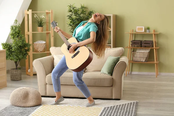 Bella giovane donna che suona la chitarra e canta a casa — Foto Stock