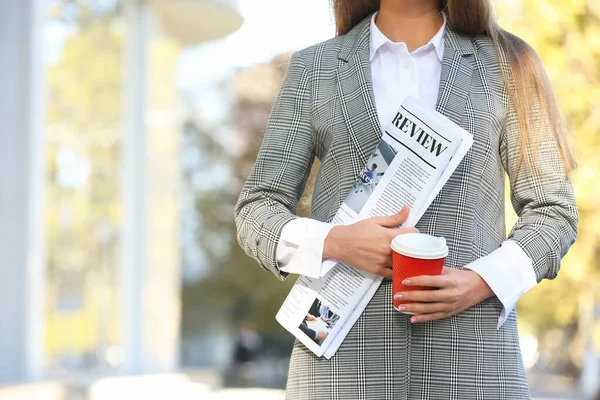 Joven empresaria con periódico y taza de café al aire libre — Foto de Stock