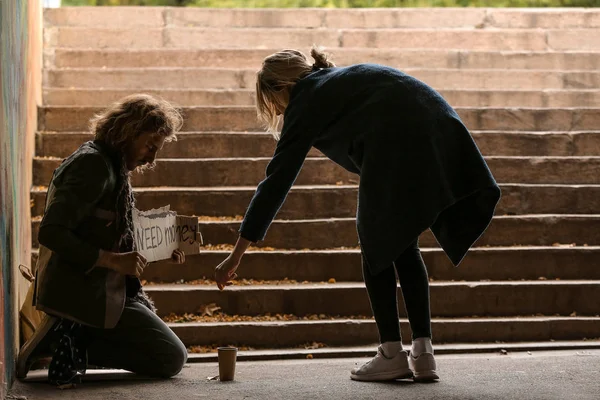 Женщина дает деньги бедному бездомному на улице — стоковое фото