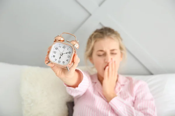 Morgens schläfrige junge Frau mit Wecker im Bett — Stockfoto