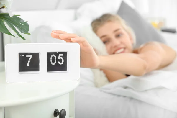 Morning of beautiful young woman turning off alarm clock in bedroom — Stock Photo, Image