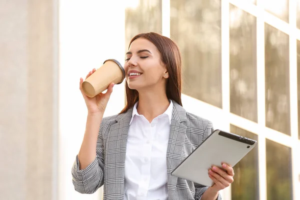 Hermosa joven empresaria con café y tableta al aire libre — Foto de Stock