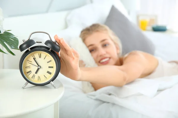 Morning of beautiful young woman turning off alarm clock in bedroom — Stock Photo, Image