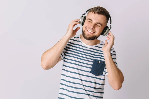 Happy young man listening to music on grey background — Stock Photo, Image
