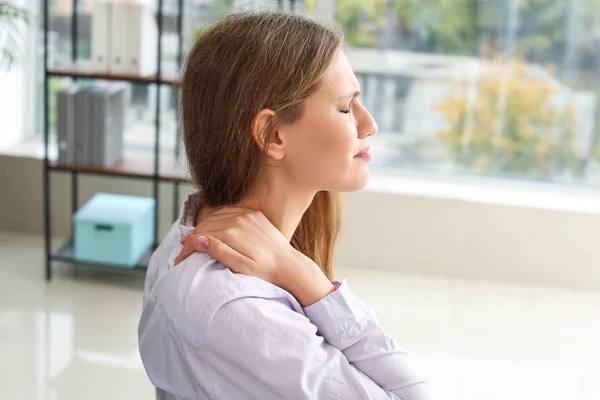 Young businesswoman suffering from back pain in office — Stock Photo, Image