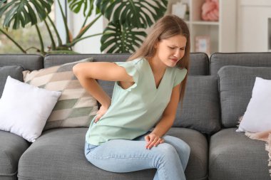 Evde sırt ağrısı çeken genç bir kadın.