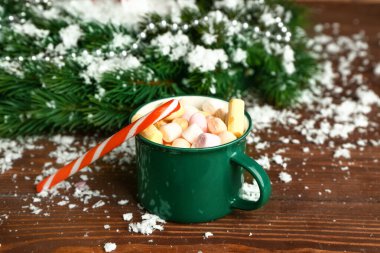 Bir kupa sıcak çikolata, Noel şekerleri, şekerlemeler ve masada kar.