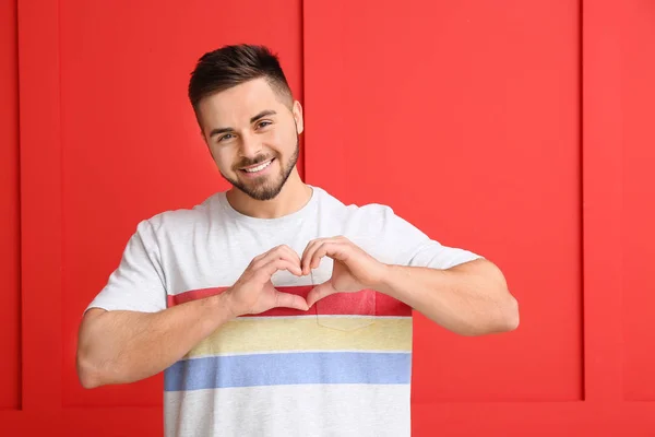 Beau homme faisant cœur avec ses mains sur fond de couleur. Fête de la Saint-Valentin — Photo