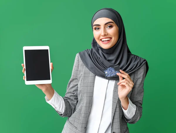 Mulher árabe bonita com tablet computador e cartão de crédito em fundo de cor — Fotografia de Stock