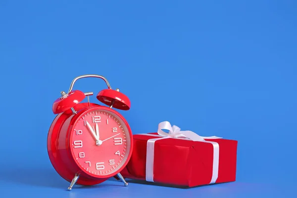 Reloj despertador con regalo de Navidad sobre fondo de color — Foto de Stock