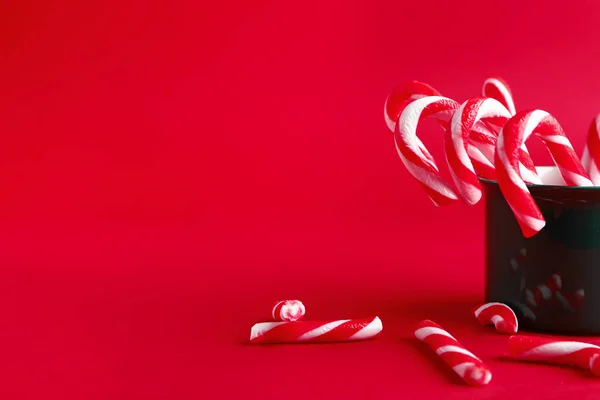 Mug with Christmas candy canes on color background — Stock Photo, Image