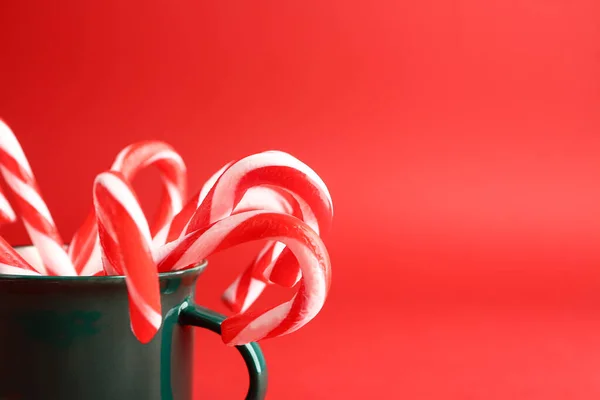 Mug with Christmas candy canes on color background, closeup — Stock Photo, Image