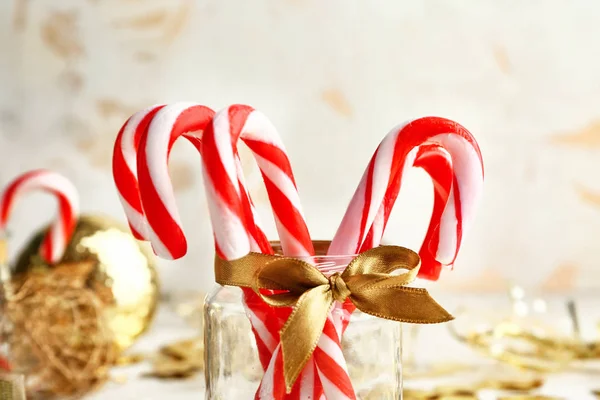 Glass jar with Christmas candy canes and decor on table — Stock Photo, Image