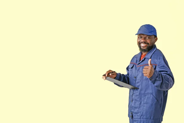 African-American car mechanic showing thumb-up on color background — Stock Photo, Image