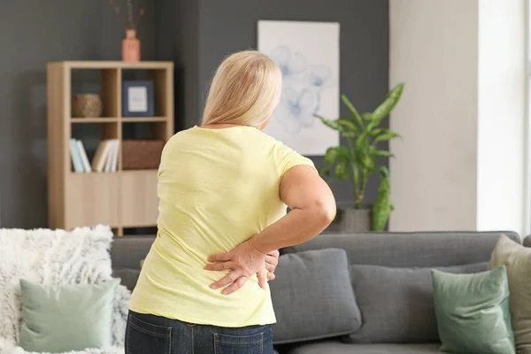 Mujer madura que sufre de dolor de espalda en casa —  Fotos de Stock