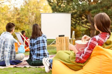 Arkadaşlar açık hava sinemasında film izliyor.