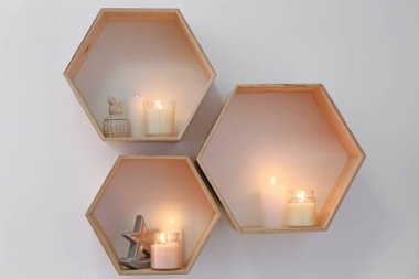 Ahşap raflarda dekoru olan parlak mumlar.