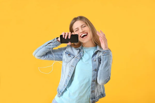Schöne junge Frau hört Musik und singt auf farbigem Hintergrund — Stockfoto