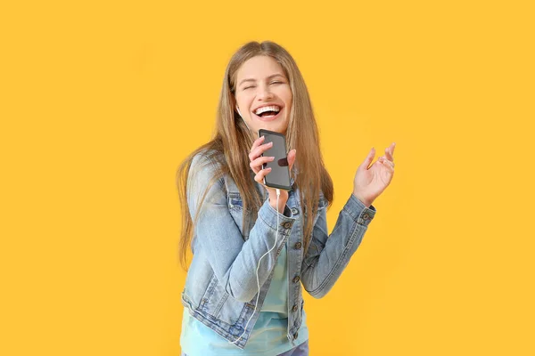 Krásná mladá žena poslech hudby a zpěvu na barevném pozadí — Stock fotografie
