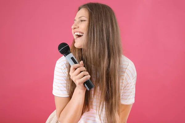 Hermosa joven cantante femenina con micrófono sobre fondo de color —  Fotos de Stock