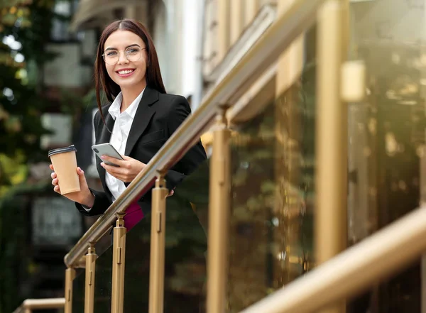 Hermosa joven empresaria con café y teléfono móvil al aire libre — Foto de Stock