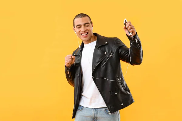 Retrato de un joven guapo escuchando música sobre fondo de color — Foto de Stock