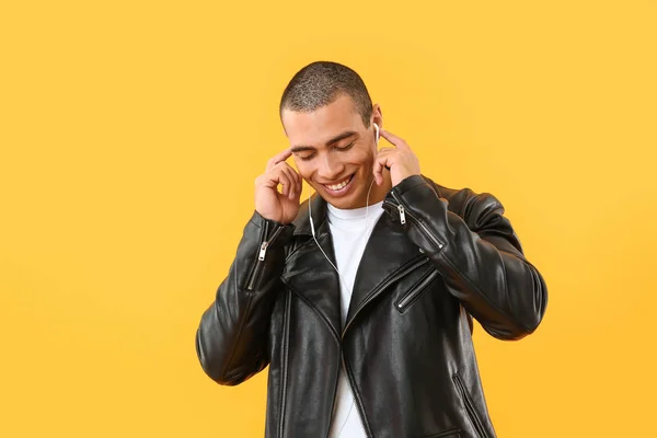 Retrato de belo jovem ouvindo música sobre fundo de cor — Fotografia de Stock