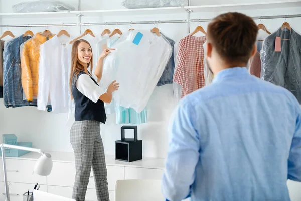 Client taking clothes from modern dry-cleaner's — Stock Photo, Image