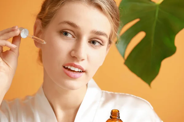 Hermosa mujer joven con producto cosmético sobre fondo de color —  Fotos de Stock