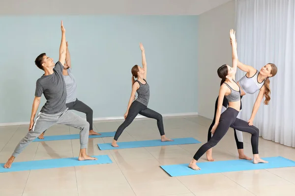 Skupina lidí cvičí jógu instruktorem v tělocvičně — Stock fotografie
