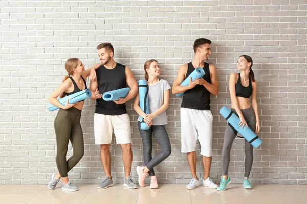 Group of people with yoga mats near brick wall — Stock Photo, Image