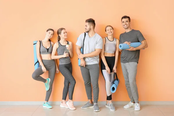 Grupo de pessoas com tapetes de ioga perto da parede de cor — Fotografia de Stock