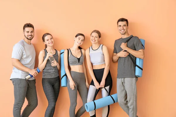Група людей з килимками йоги біля кольорової стіни — стокове фото