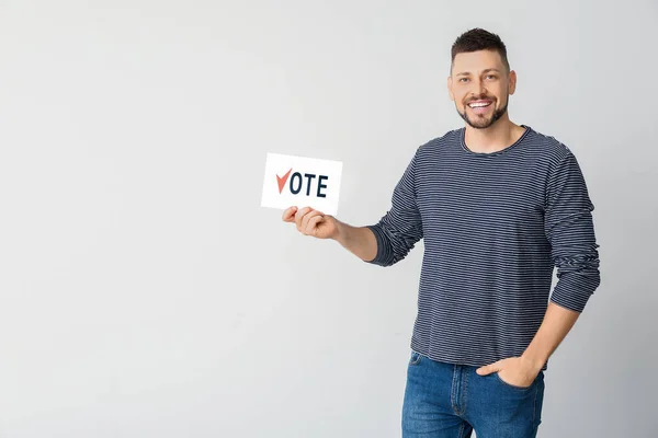 Mężczyzna trzyma papier z tekstem Głosuj na jasnym tle — Zdjęcie stockowe